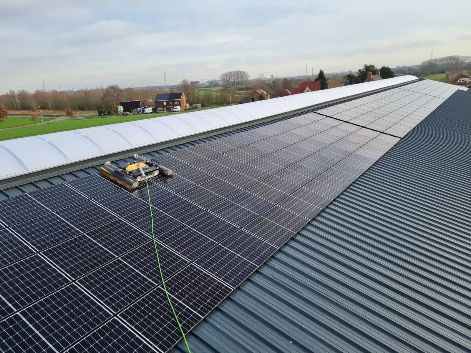 Robot de nettoyage relié à un tuyau d’eau pure sur des panneaux solaires en toiture