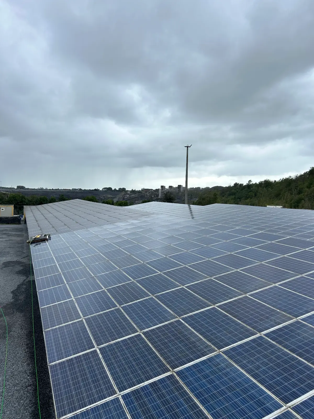 Grande toiture équipée de panneaux solaires sous un ciel nuageux