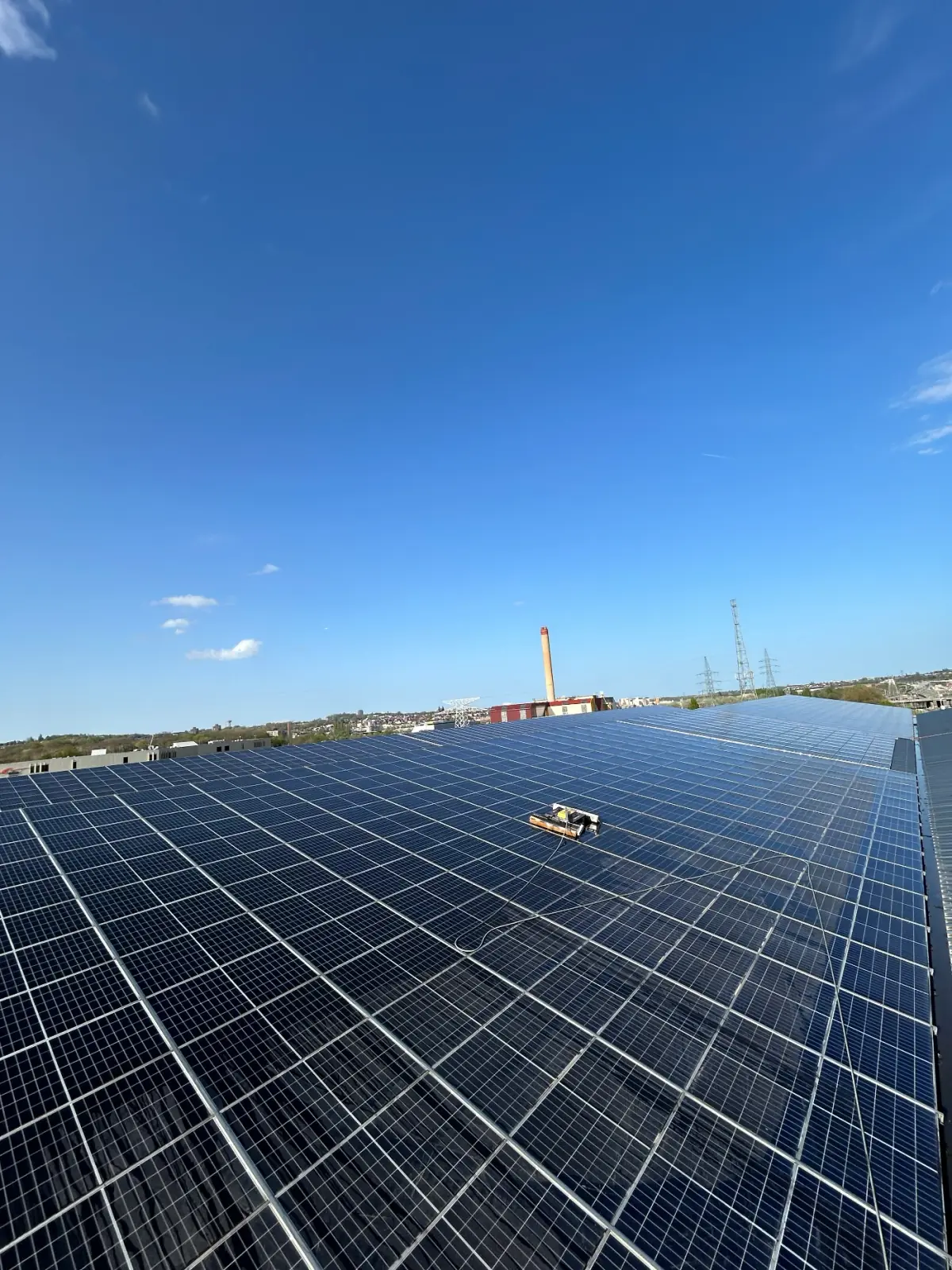 Robot de nettoyage sur un grand champ de panneaux solaires sous un ciel bleu