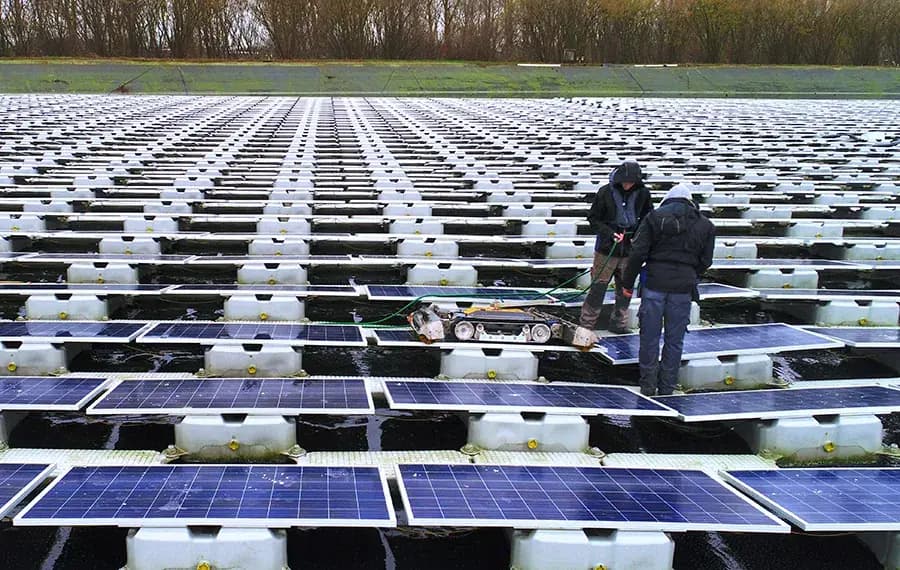Zwei Techniker von Solarco mit einem Reinigungsroboter auf einer schwimmenden PV-Anlage