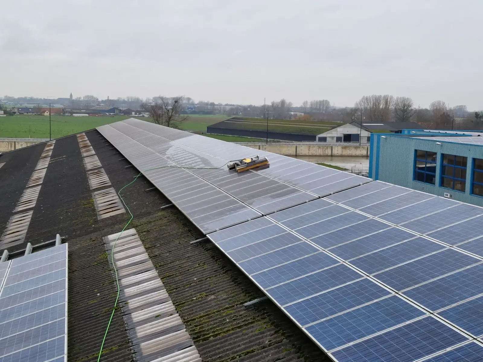 Robot de nettoyage sur un toit en pente équipé de panneaux solaires, en milieu rural