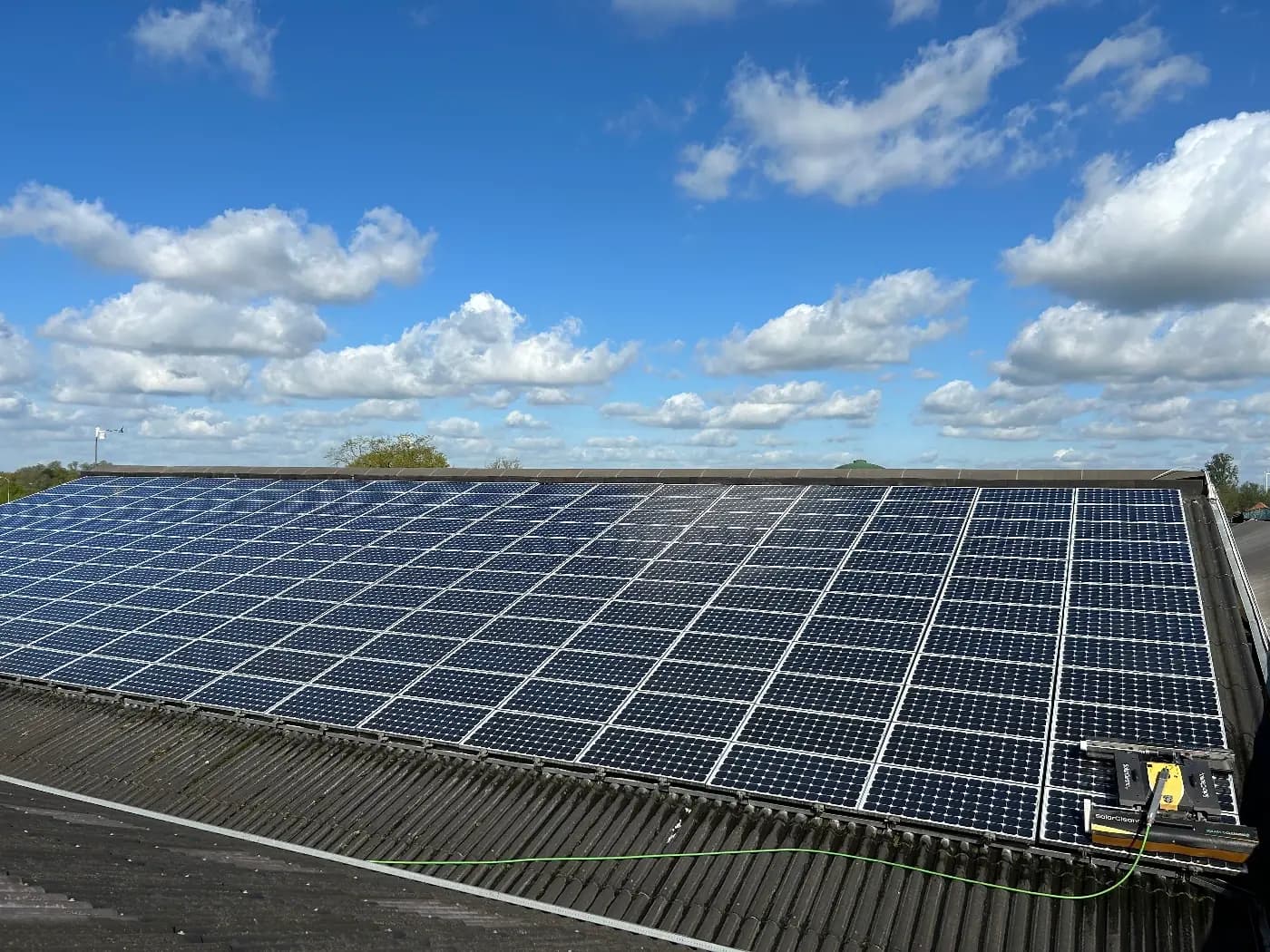 Hangar agricole équipé de panneaux solaires et d’un robot de nettoyage, sous un ciel bleu