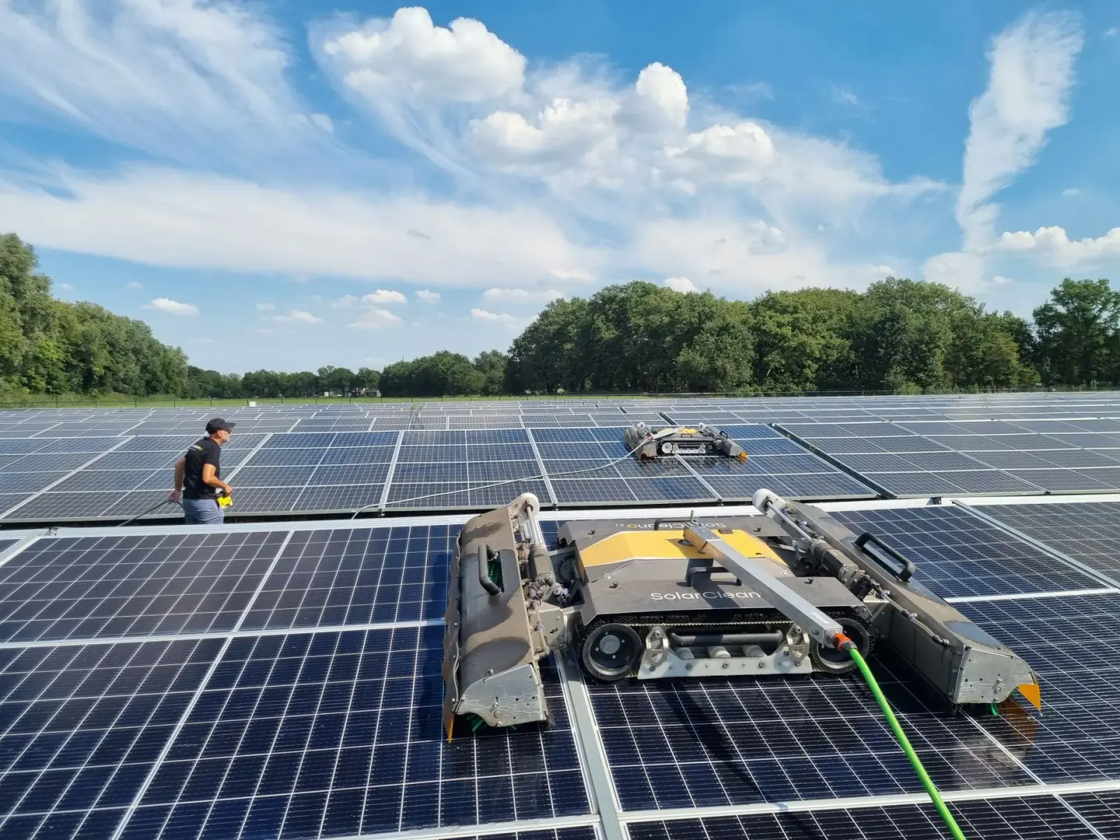 Zwei Reinigungsroboter von Solarco und ein Techniker auf einem großen Firmendach
