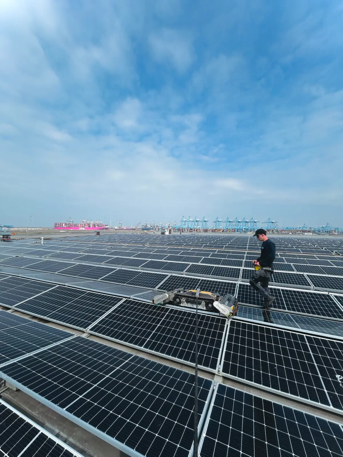 Opérateur Solarco avec un robot de nettoyage sur une grande toiture en zone portuaire