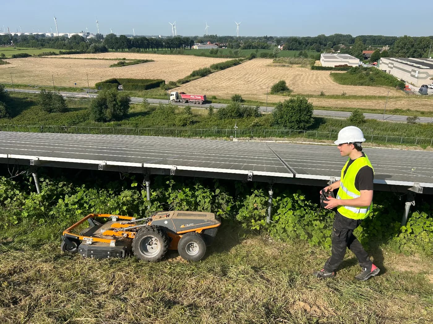 Solarco-Techniker steuert einen Mähroboter zwischen den Modulen eines Solarparks